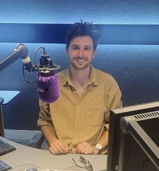 Ben Imber, founder of Trelawny Production, at a microphone in a radio studio